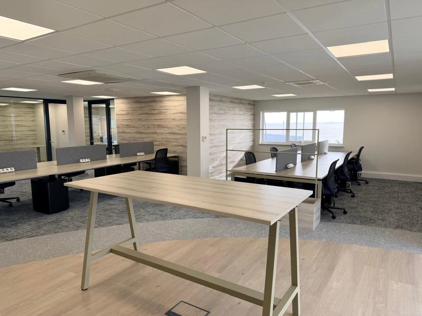 Standing height breakout table with open-plan desks and suspended ceiling at Boluda Towage