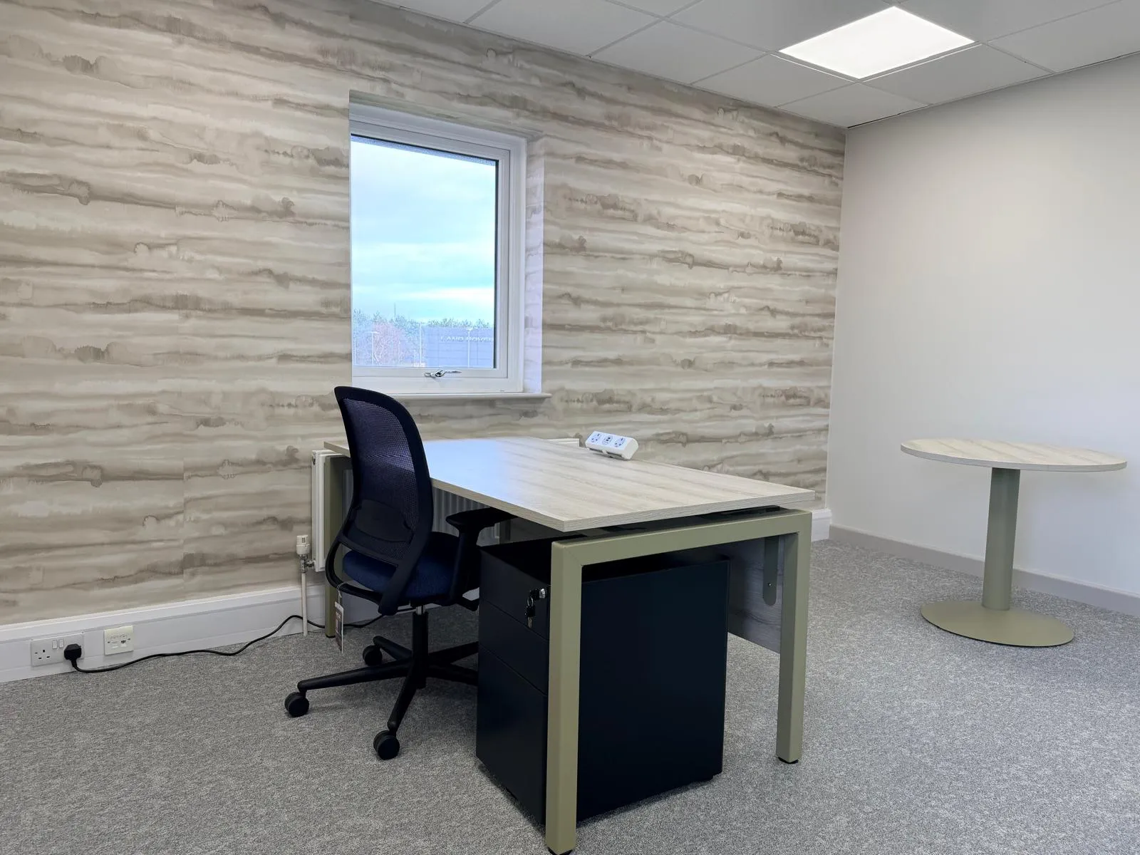 Private office with feature wallpaper, desk, task chair, and round meeting table at Boluda Towage