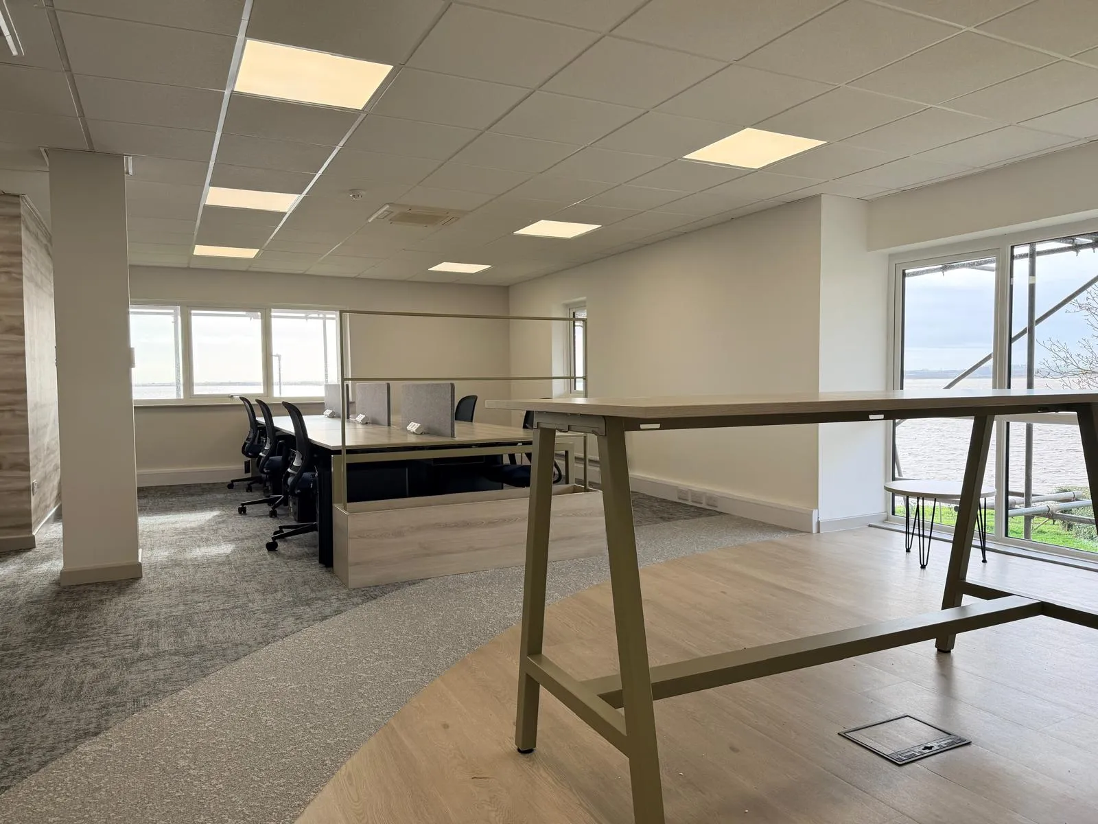 Breakout zone with standing height table, vinyl plank flooring, and open-plan desks at Boluda Towage