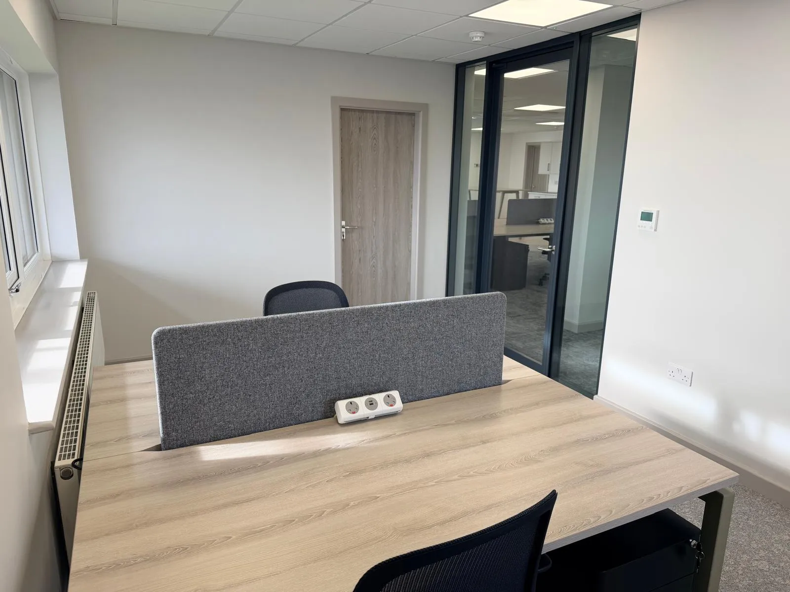 Two-person private office with bench desk, privacy screen, and glass wall at Boluda Towage